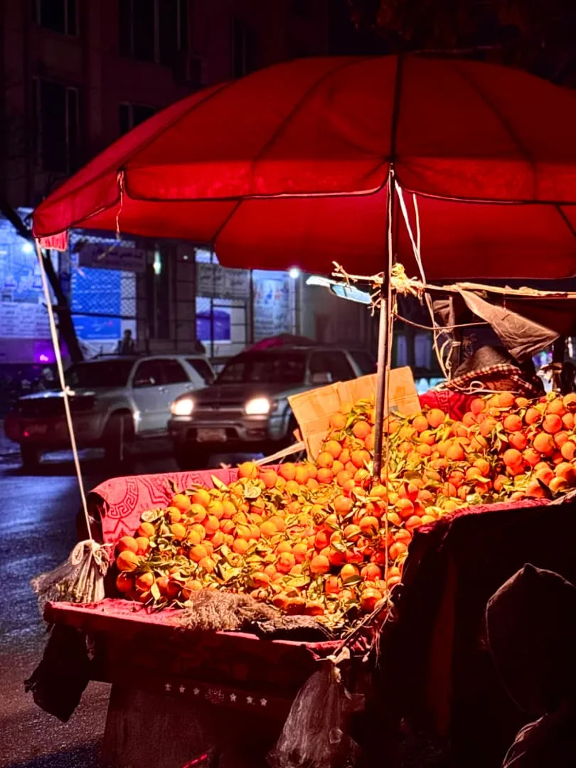 A market at dusk under a red umbrella